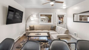 Un salon avec un canapé d’angle beige, une table basse et un ventilateur de plafond.