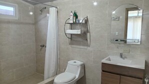 Ein Badezimmer mit Dusche, Toilette, Waschbecken und Spiegel.