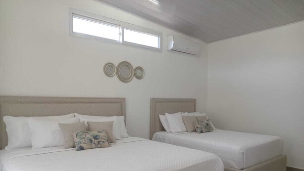 Ein Hotelzimmer mit zwei Betten, einem großen Fenster und einer Wand-Klimaanlage.