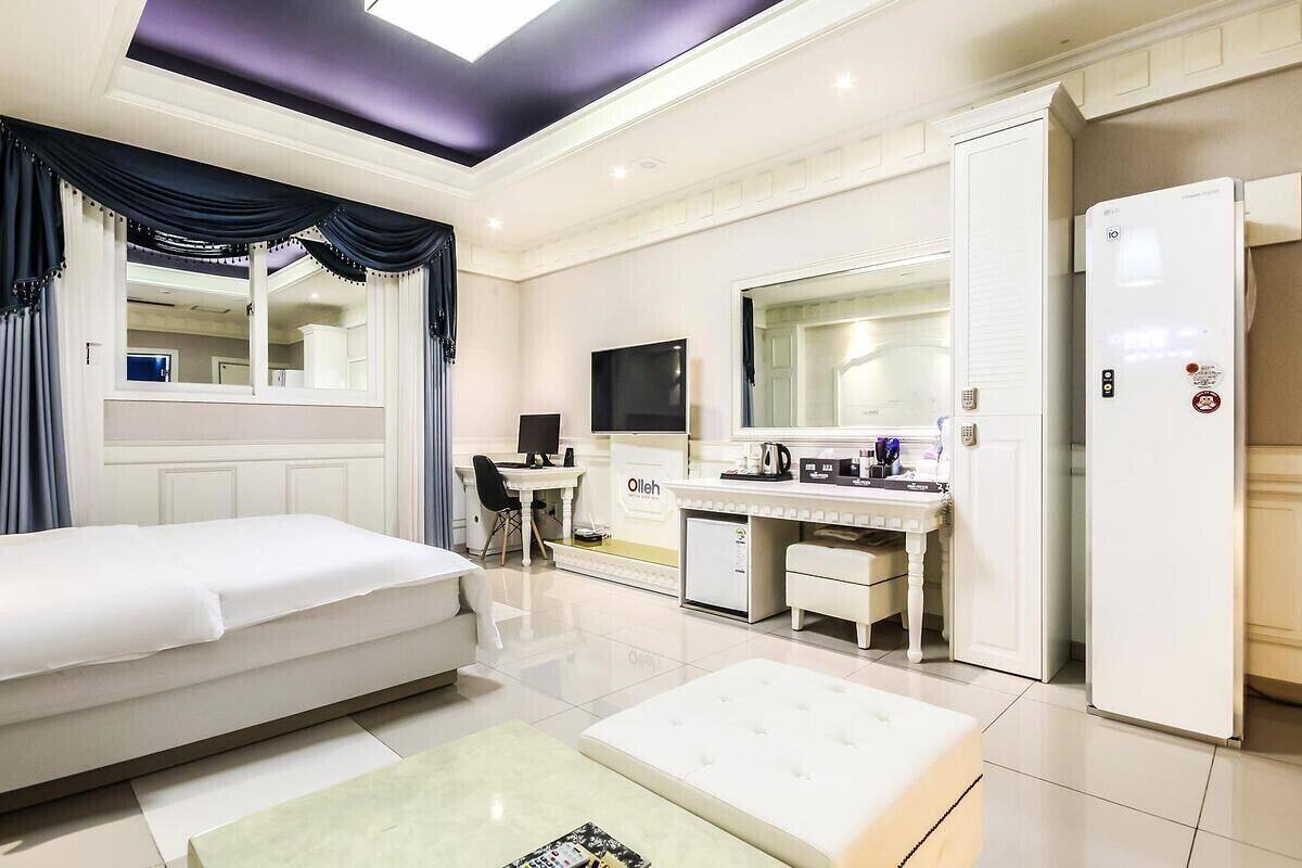 Une chambre d’hôtel équipée d’un lit, d’un bureau, d’un miroir, d’une télévision et d’un mini-bar.