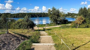 Un sendero que lleva a un lago con una cubierta de madera y una zona cercada.