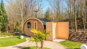 Una cabaña de madera con techo curvo, un porche pequeño y una ventana.