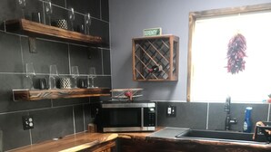 Une cuisine moderne avec des carreaux de couleur sombre, des meubles en bois et un four à micro-ondes encastré.