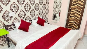Una cama bien hecha con ropa de cama blanca y roja, un papel tapiz estampado y un espejo en la pared.