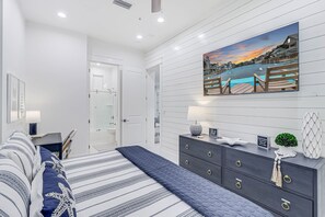 Een moderne slaapkamer met een bed, een dressoir, een nachtkastje en een schilderij van een watergezicht.