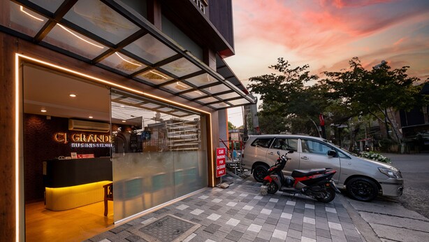 A hotel entrance with a reception desk, a car parking sign, and a motorcycle parked outside. - C J Grande Business Hotel (Kanayannur)