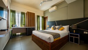 A bedroom with a wooden bed, a desk, and a ceiling fan. - C J Grande Business Hotel (Kanayannur)