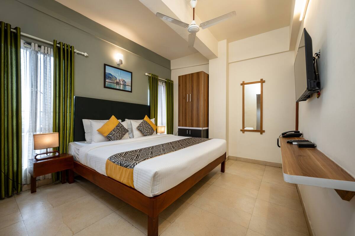 Een hotelkamer met een bed, nachtkastje, televisie, kledingkast en spiegel.