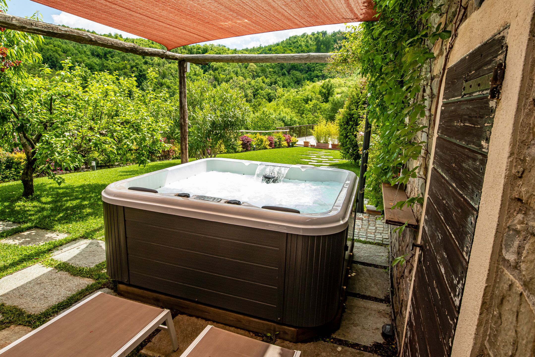 Un jacuzzi en un jardín con un porche de madera.