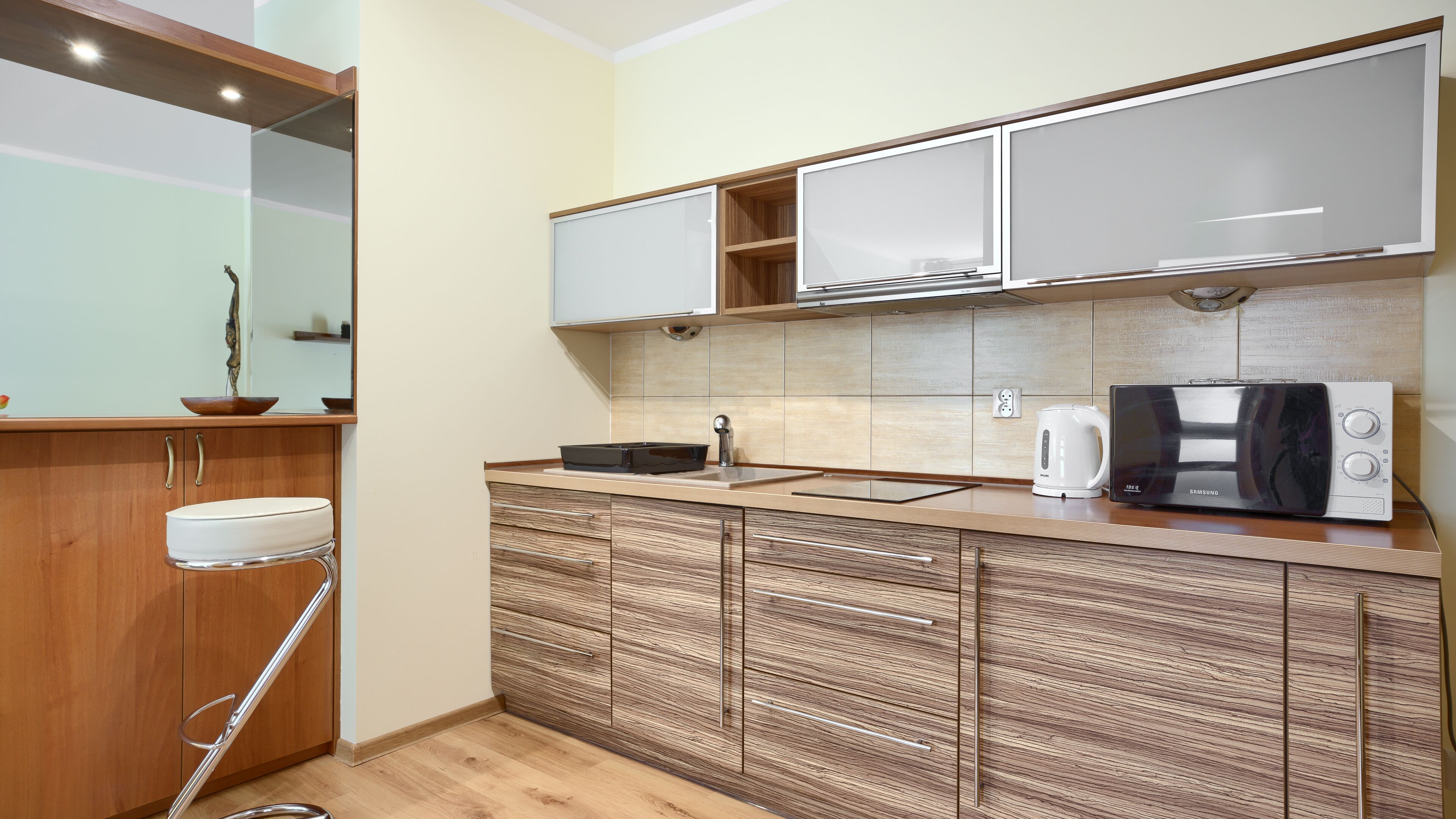 A compact kitchen with wooden cabinets, a built-in microwave, and a sink.