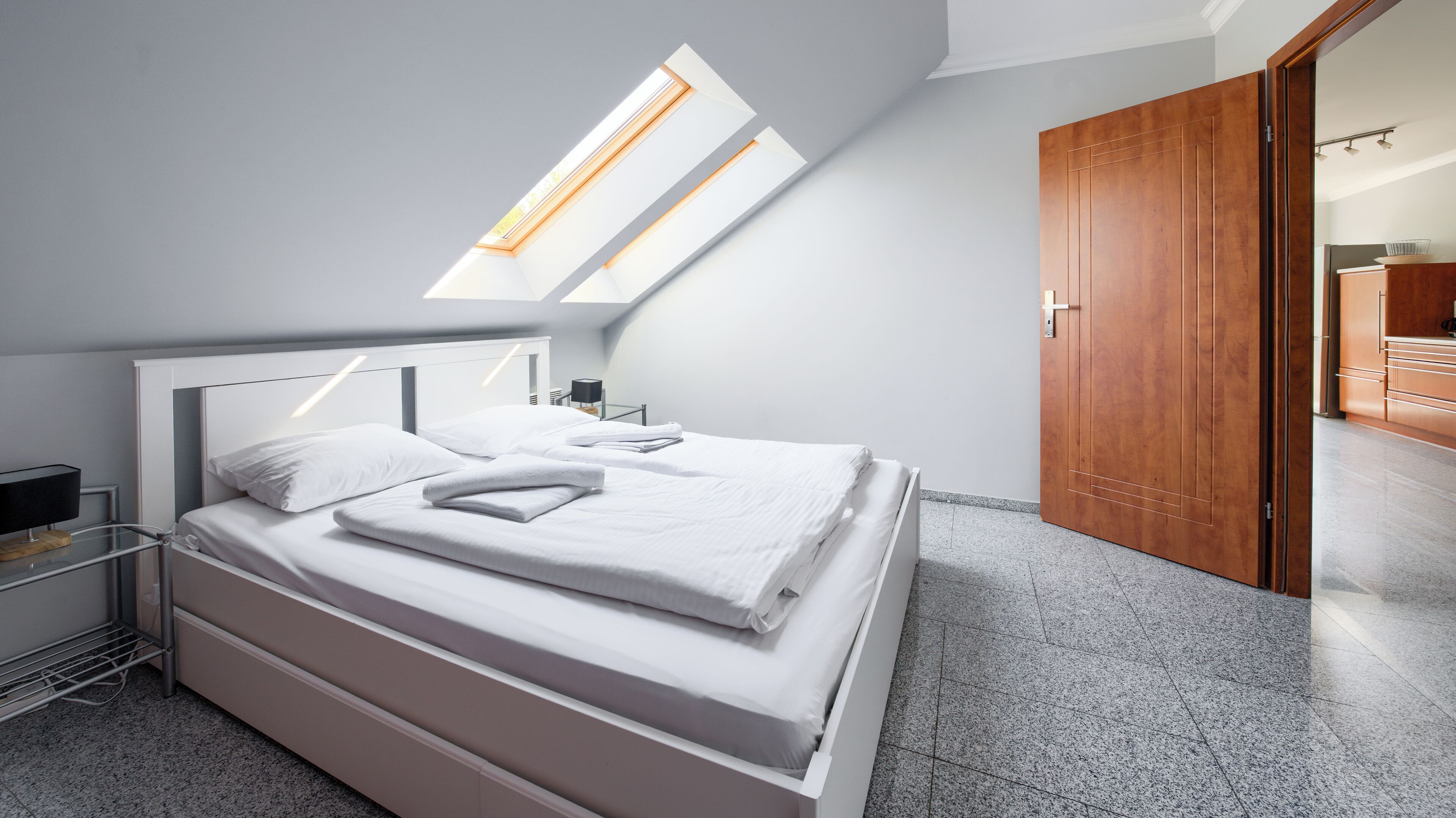 Une chambre moderne avec un lit, une fenêtre de toit et une porte en bois.