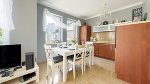 A modern kitchen with a dining area, a TV, and a chandelier. - Apartamenty Sun & Snow Morskie Oko (Miedzyzdroje)