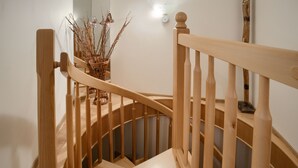 A wooden staircase with a handrail, a wicker basket with branches, and a wall-mounted light fixture. - Apartamenty Sun & Snow Morskie Oko (Miedzyzdroje)