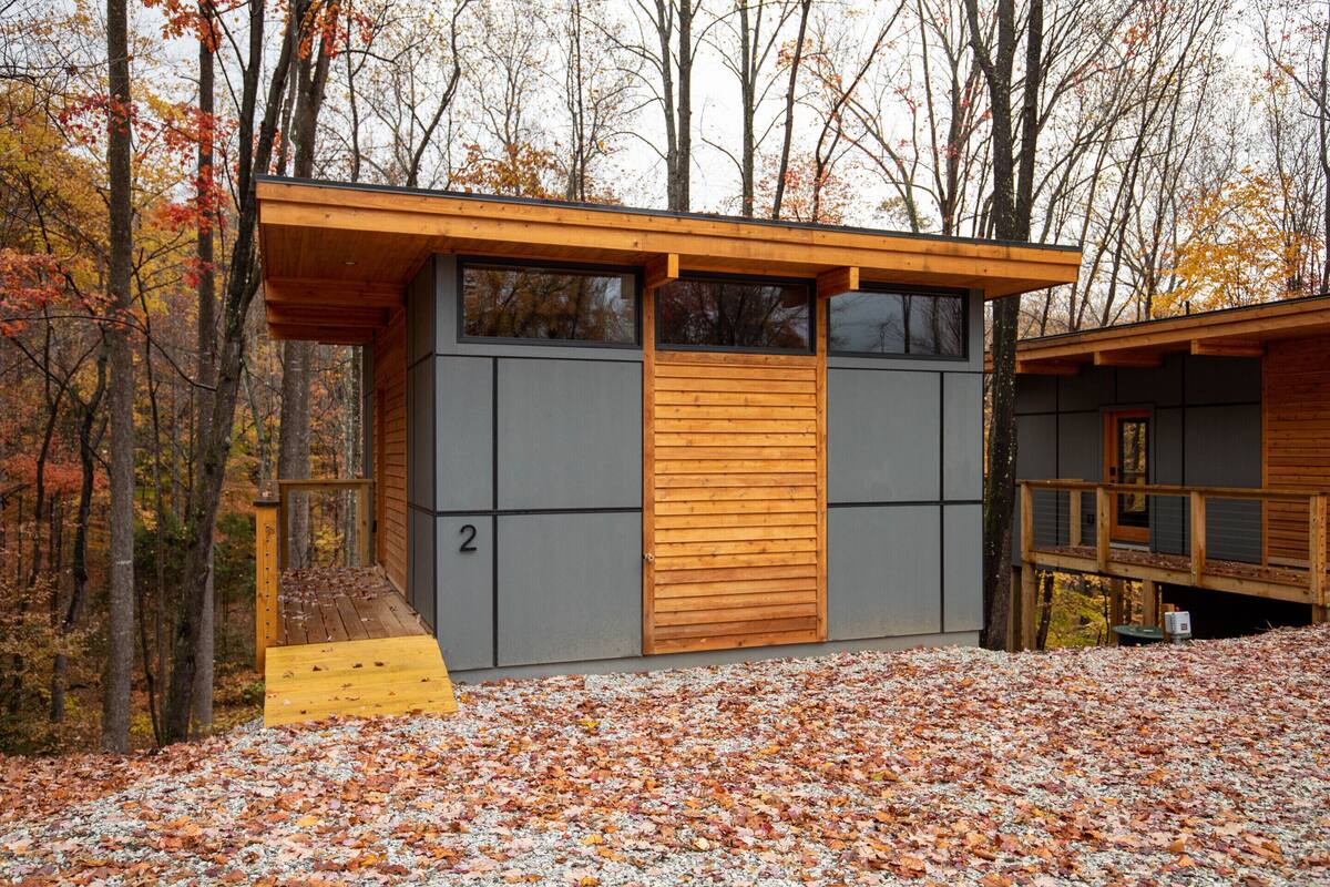 A modern cabin with a wooden deck, large windows, and a number '2' on the side.