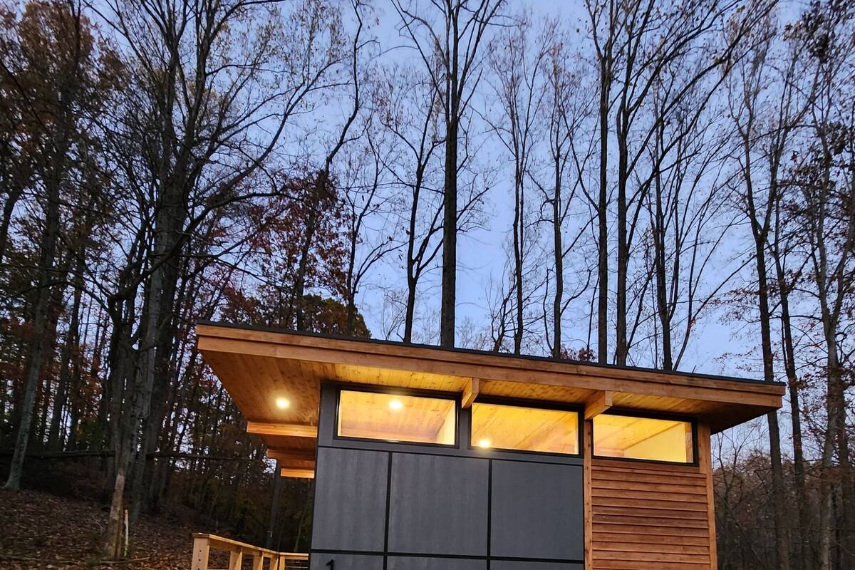 A modern cabin with a wooden deck and a large sliding door.