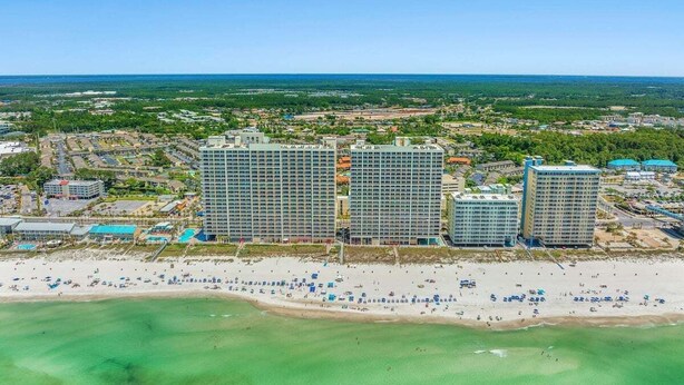 Un complexe hôtelier situé sur la côte, composé de plusieurs immeubles de grande hauteur, donnant sur la plage et offrant une vue dégagée sur l’océan.