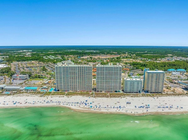 A coastal hotel complex with multiple high-rise buildings, a beachfront, and a clear view of the ocean.