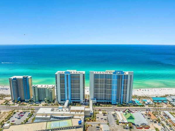 A beachfront hotel with multiple high-rise buildings, a beach, and a clear view of the ocean.