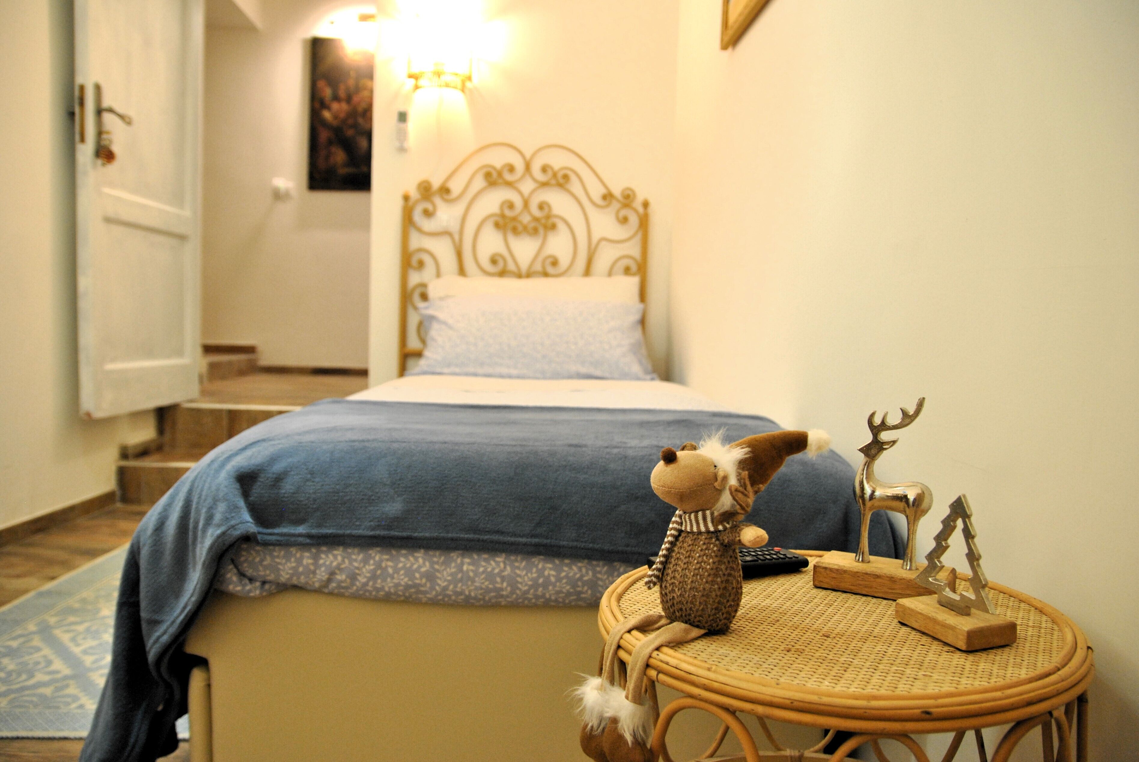 A bedroom with a bed, a wicker chair, and a small table with decorative items.