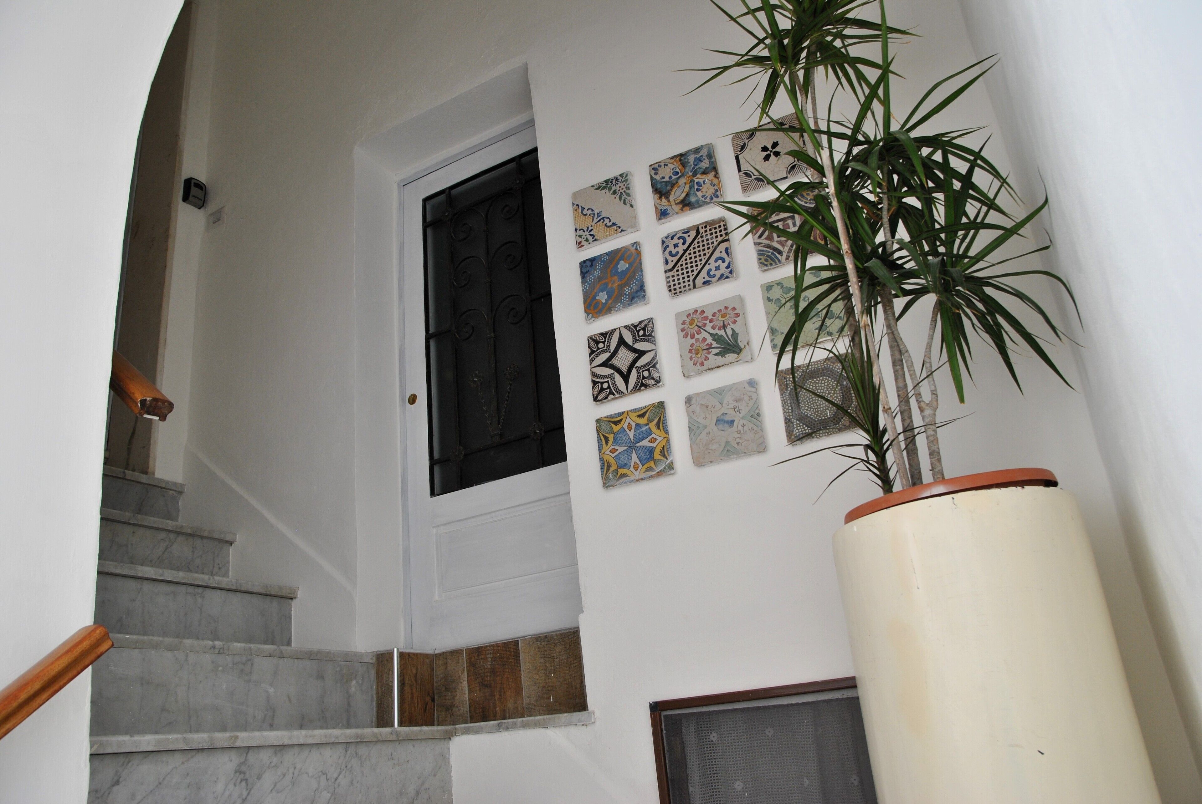 Un escalier avec une porte blanche et un mur décoré de différents carreaux.