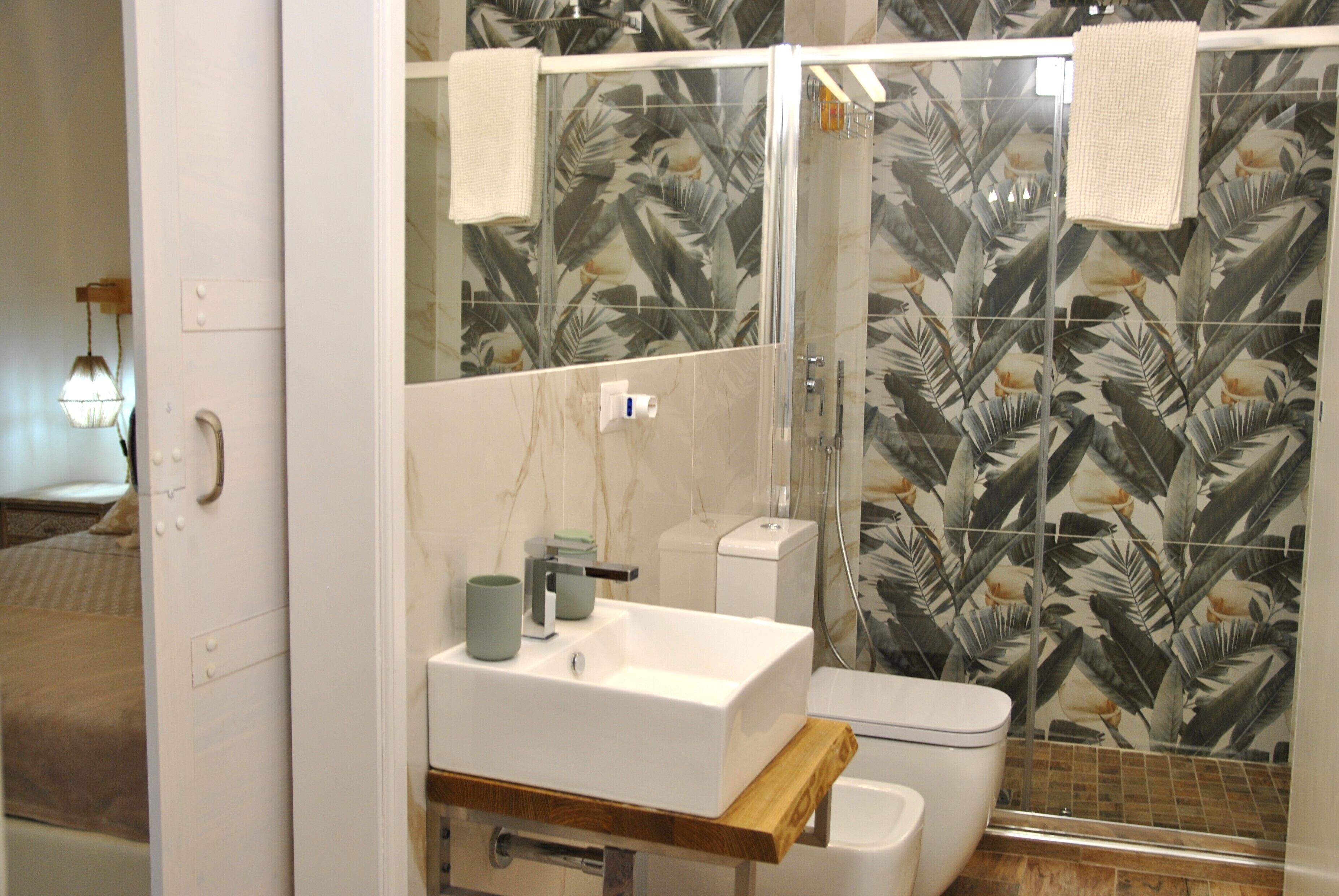 Un bagno con lavandino, water e doccia bianchi. Un asciugamano è appeso alla porta della doccia.