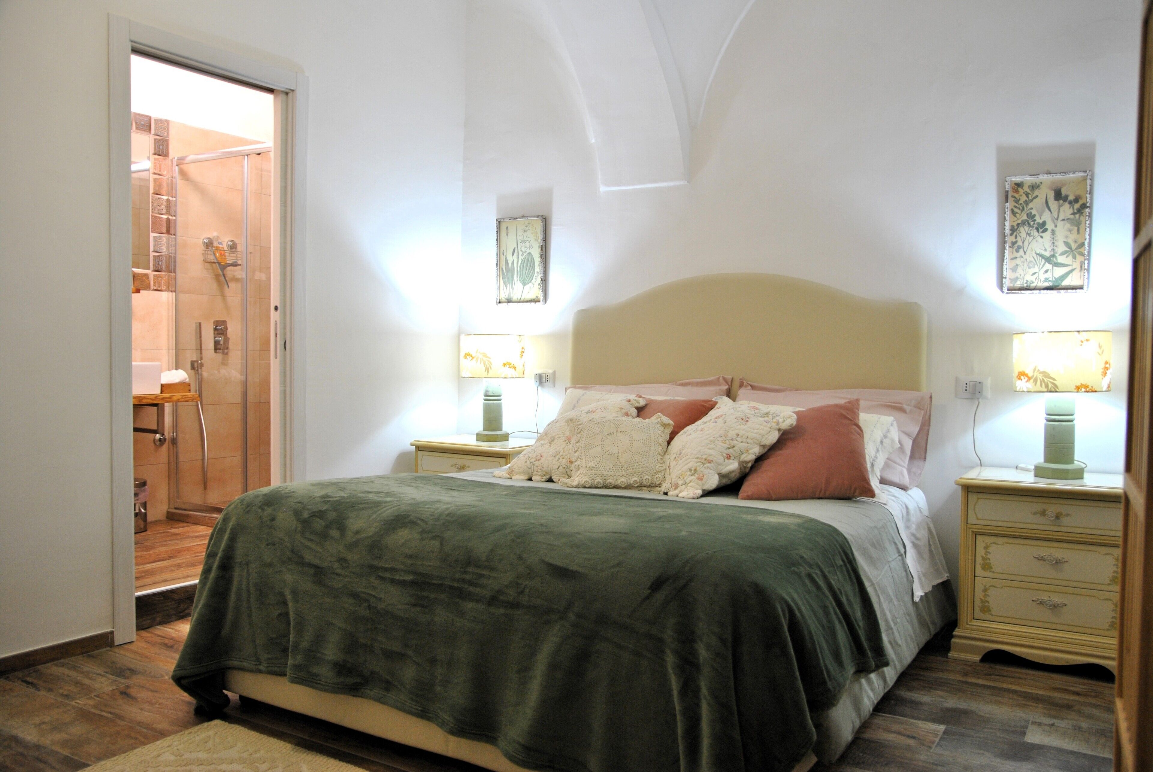 A bedroom with a bed, nightstands, a lamp, and a door leading to a bathroom.