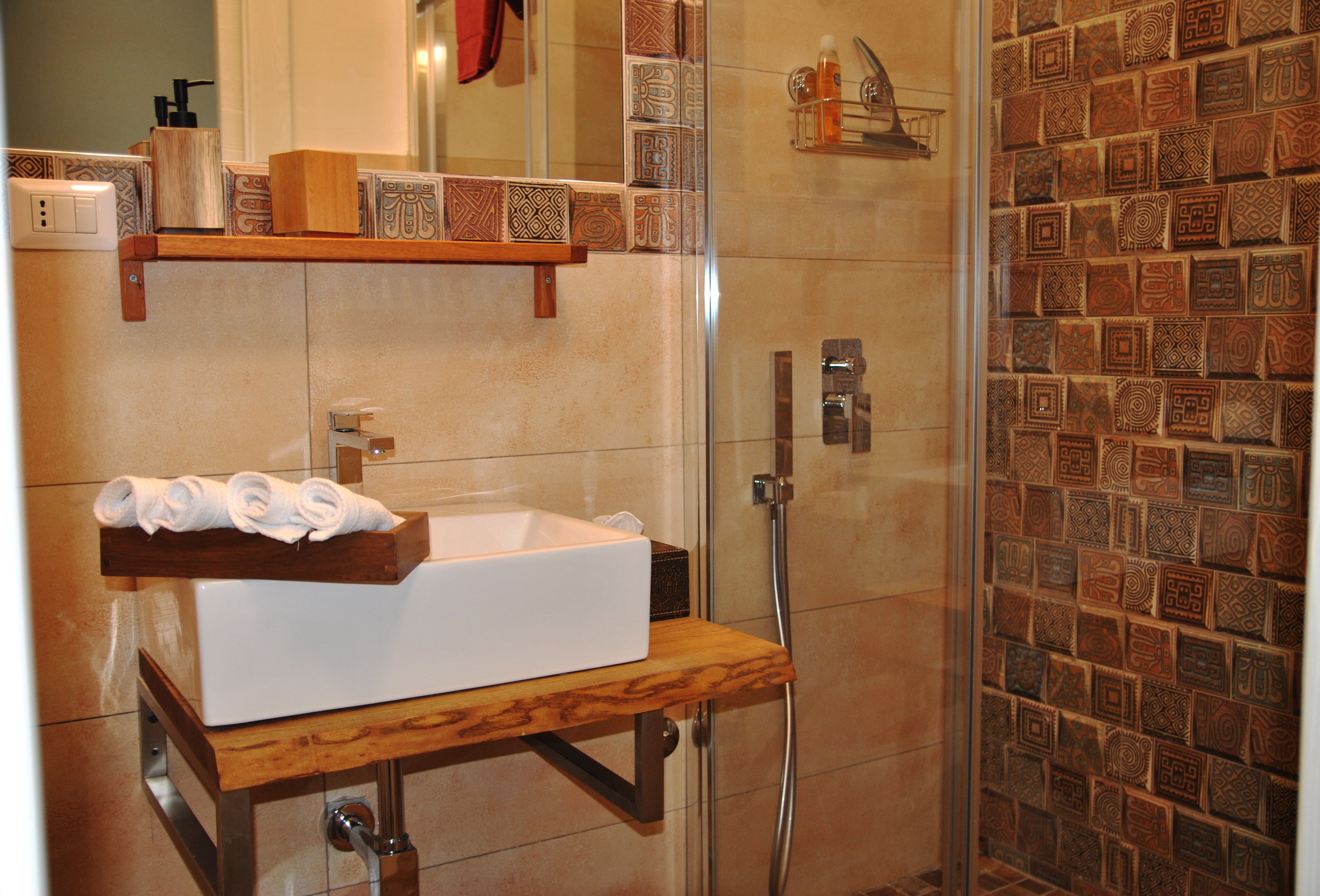 Une salle de bain avec un meuble-lavabo en bois, un lavabo blanc et un espace douche.