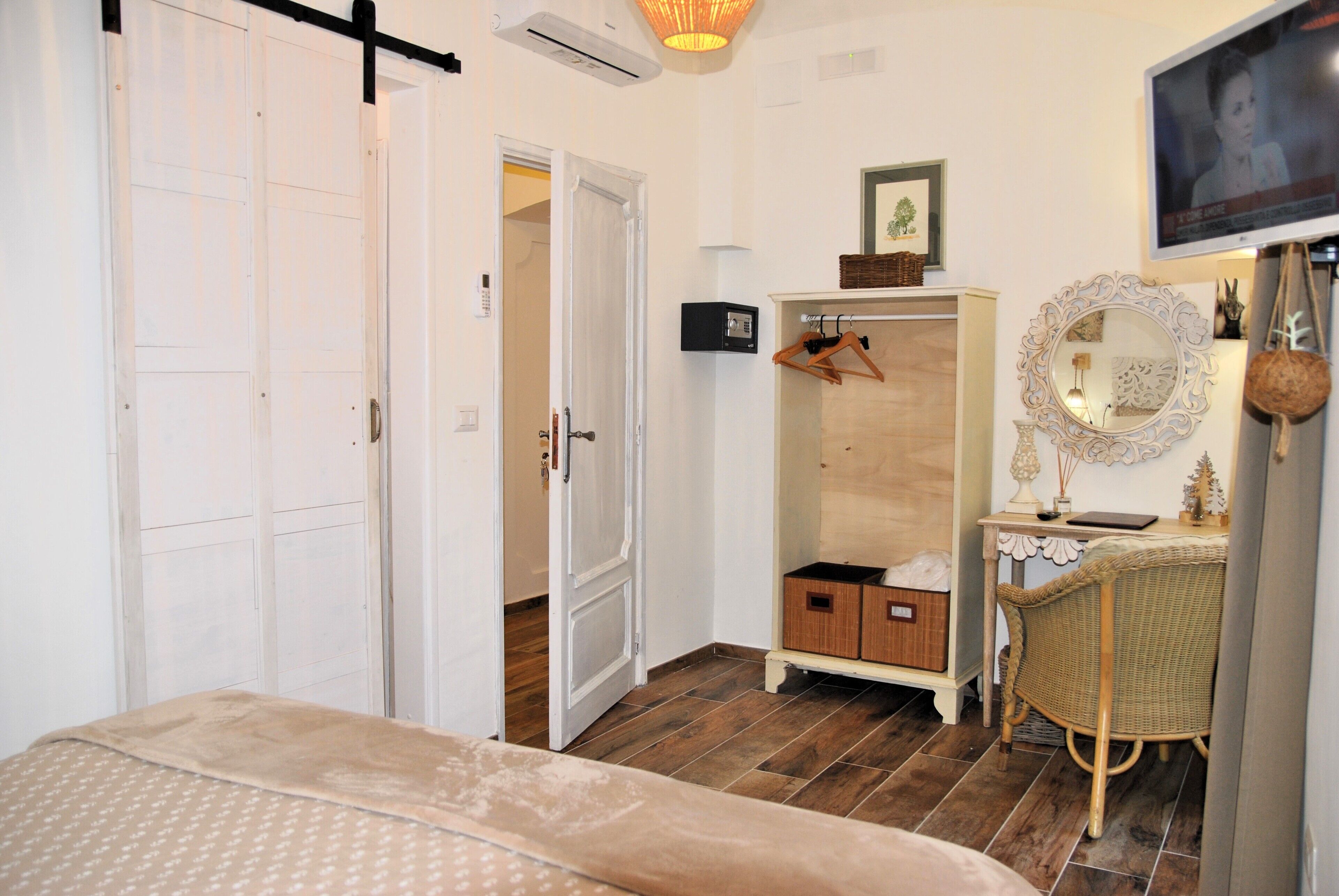A bedroom with a bed, a wardrobe, a mirror, and a television.