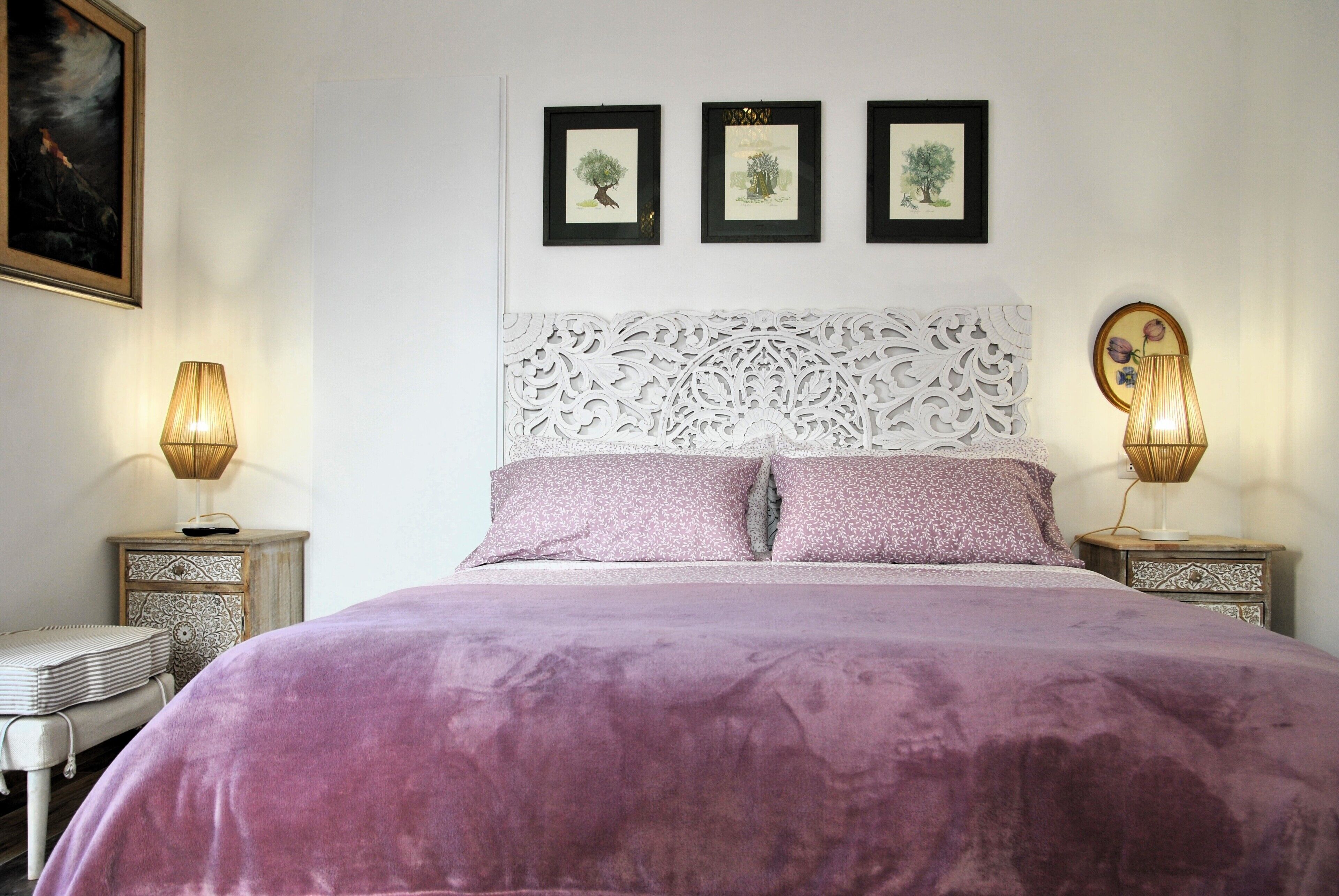 Un dormitorio con una cama grande, dos mesitas de noche y un cabecero decorativo.
