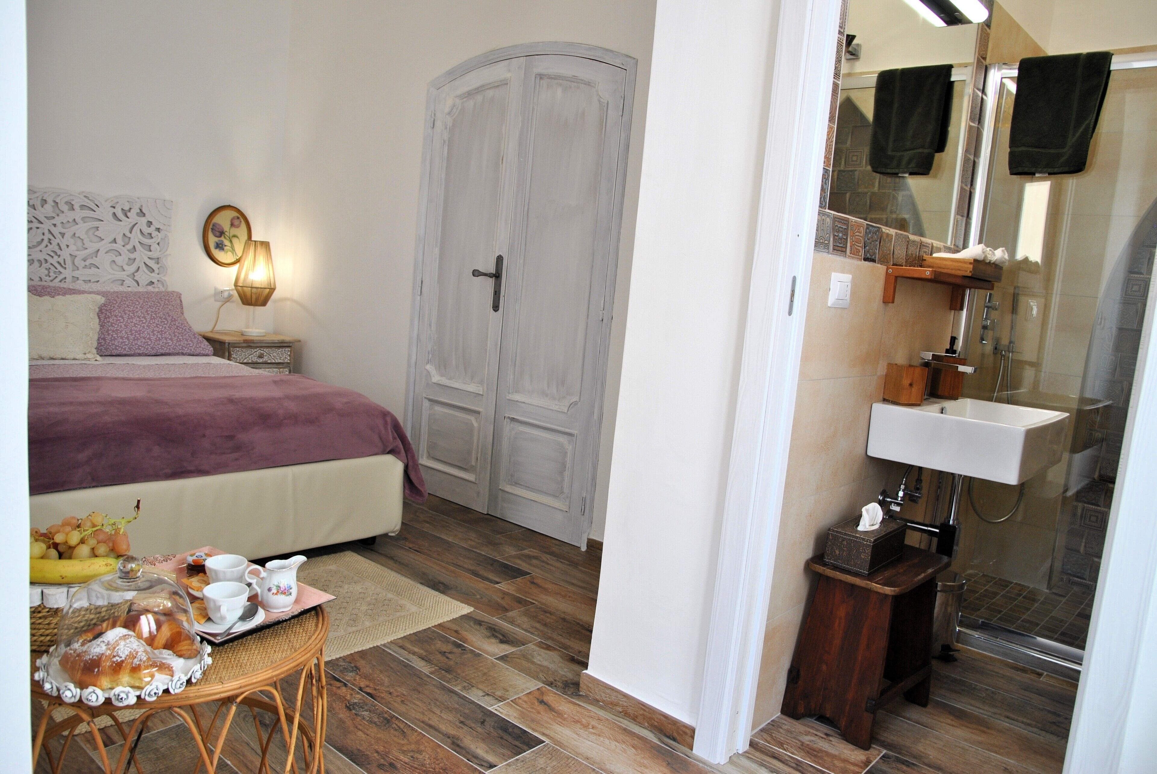 Un dormitorio con cama, mesita de noche y una pequeña mesa con artículos para el desayuno.