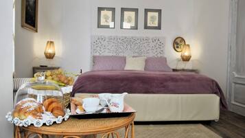 Een netjes opgemaakte slaapkamer met een bed, nachtlampjes, een decoratief hoofdeinde en een ontbijtkarretje met gebak en een koffiepot.