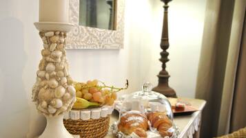 A table with a decorative lamp, a basket of grapes, and a tray of pastries.