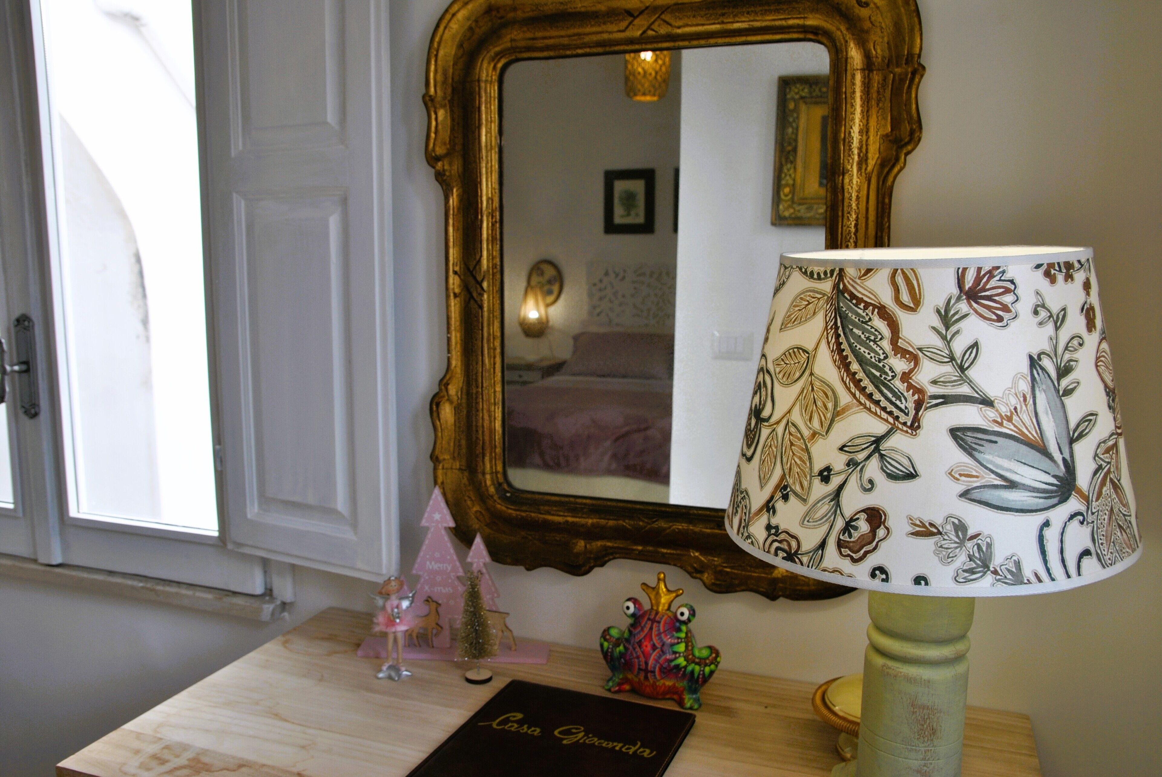 A room with a wooden table, a decorative lamp, a mirror, and a door.