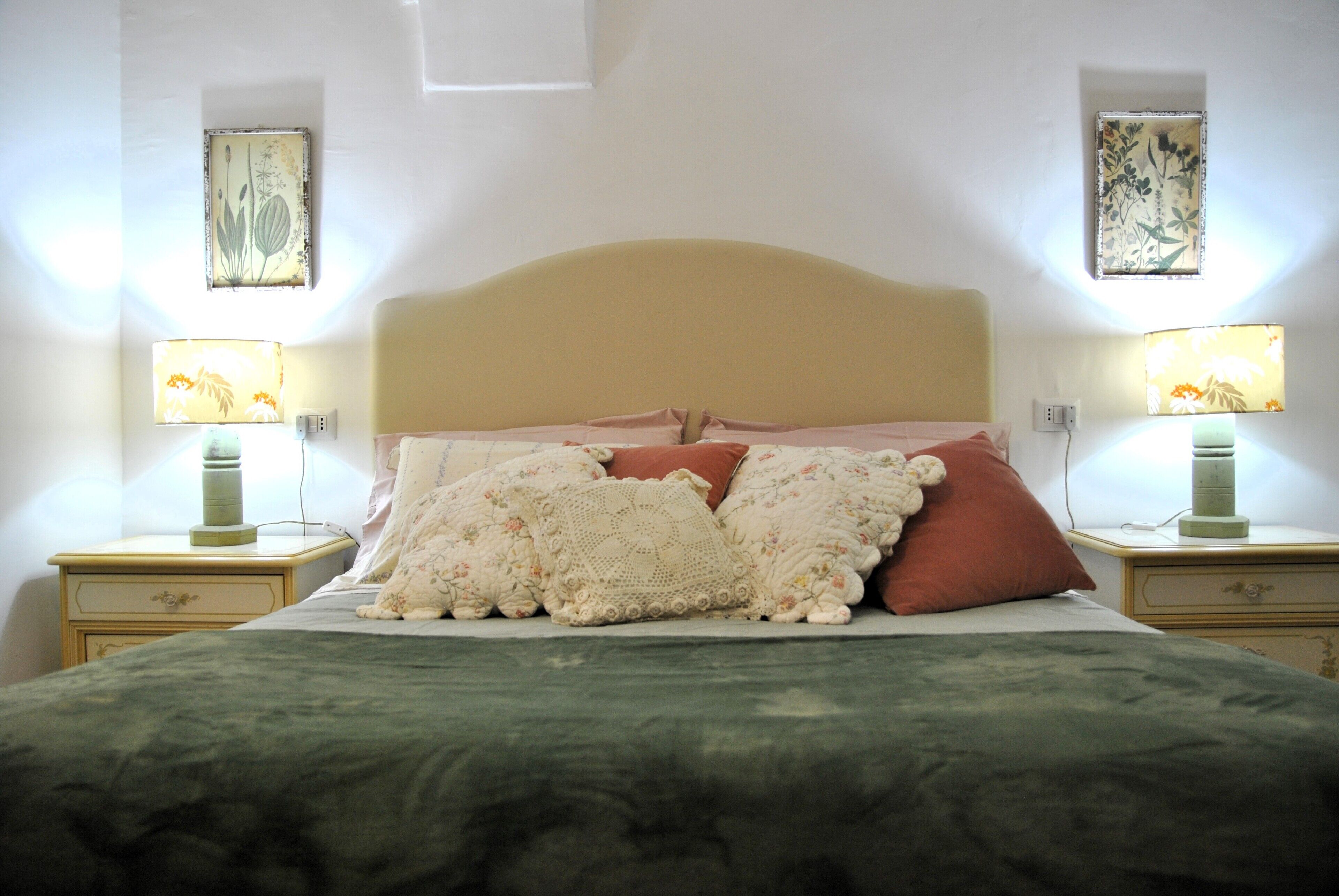A neatly made bed with floral bedding and two nightstands with lamps.