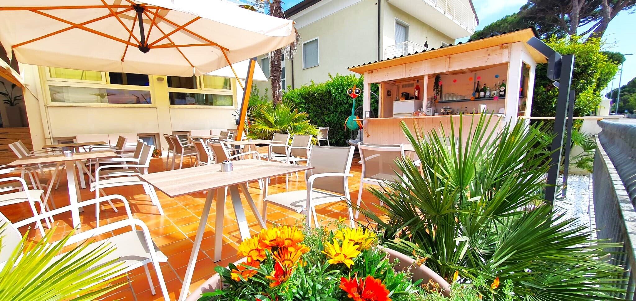 An outdoor dining area with tables and chairs, a covered seating area, and a bar.