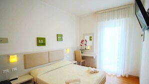 A hotel room with a bed, a desk, a chair, and a TV. - Hotel B&B Manuela (Cervia)