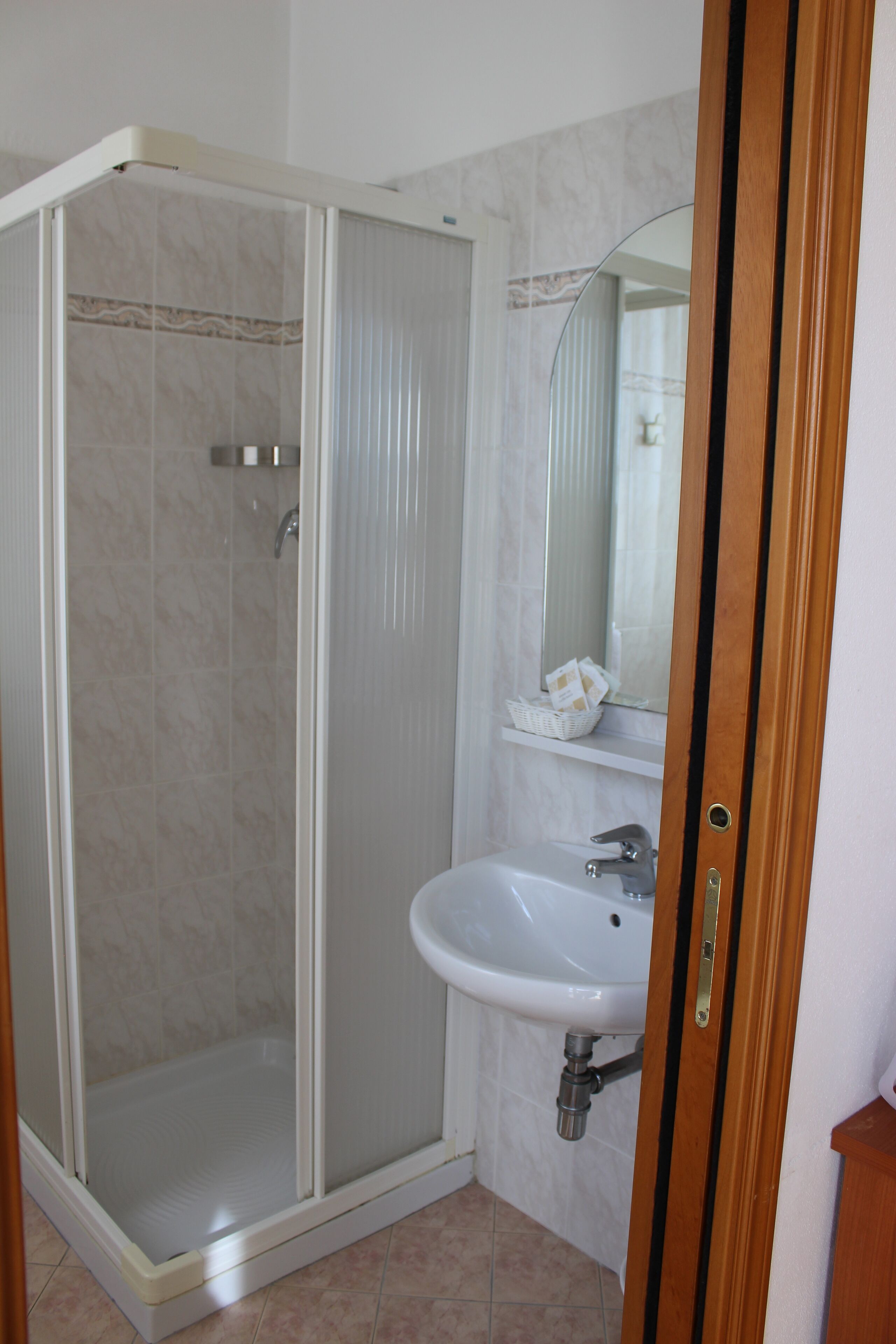 A bathroom with a glass-enclosed shower, a white sink, and a mirror above it.