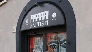 Een winkel met een zwart luifel en een bord met de tekst 'BATTISTI' boven de ingang.