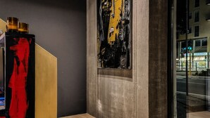 Een modern interieur met een betonmuur, een groot abstract schilderij en een houten vloer.