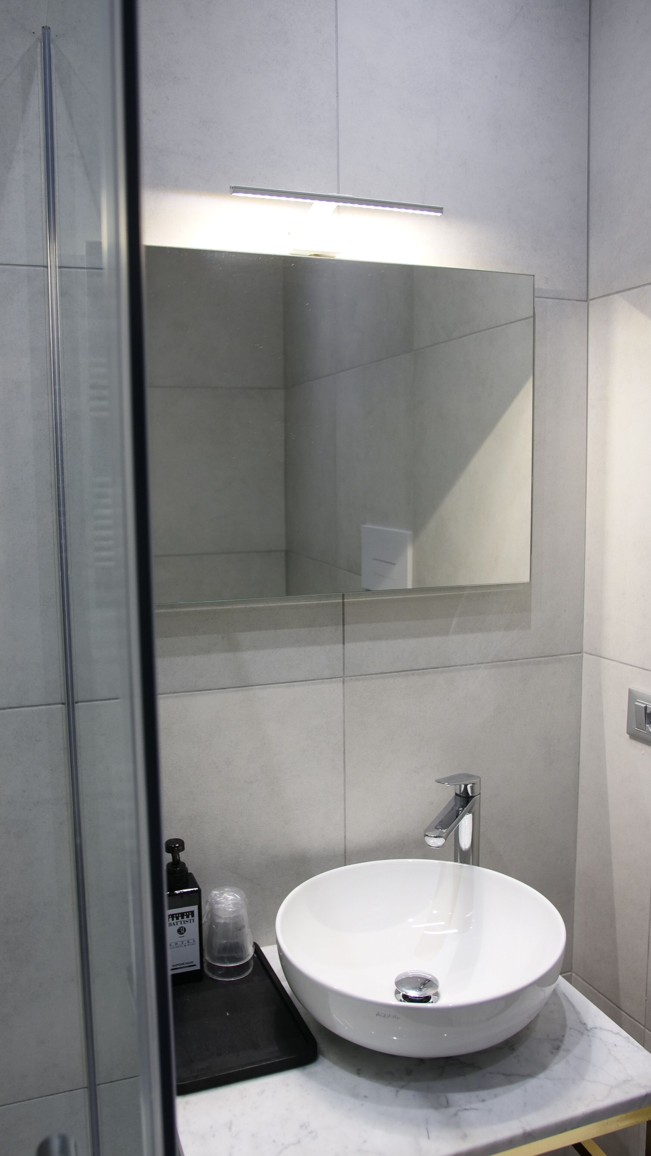 A bathroom with a white sink, a mirror above it, and a shower area to the left.