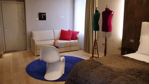 Een hotelkamer met een bank, een stoel, een tafeltje, een lamp en een bed.