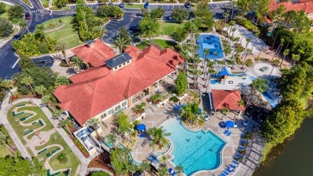 An aerial view of a resort with a large swimming pool, tennis courts, and a red-roofed building. - Sunnyside Villa 6 Bedroom Home by RedAwning (Kissimmee)