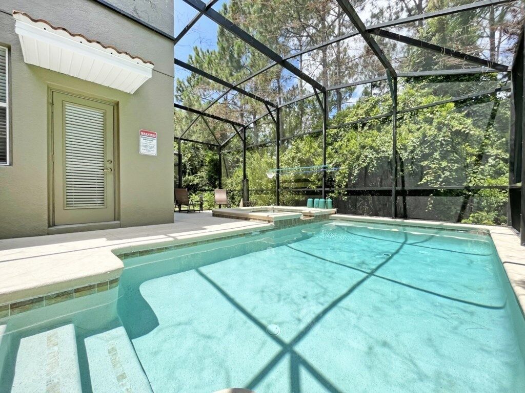 Una piscina con una cerca de metal de seguridad, una puerta con ventanal y un cartel en la puerta.