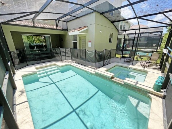 Un espace piscine doté d’une structure fermée par des parois de verre, d’un jacuzzi séparé et d’un petit coin salon extérieur.