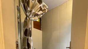 Une salle de bain avec des toilettes, un rideau de douche, un tapis bleu et un sol carrelé.