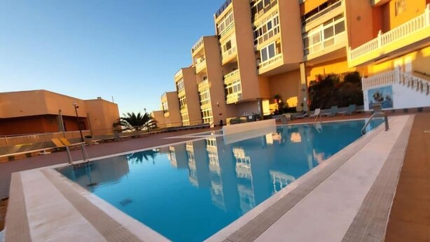 A swimming pool with a clear blue water surface, surrounded by a tiled deck. - Descanso Asegurado en Ambiente de Calma (CN)