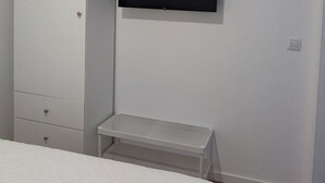 A bedroom with a bed, a wardrobe, a TV mounted on the wall, and a small table. - Descanso Asegurado en Ambiente de Calma (CN)