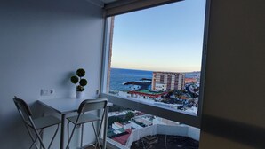 A room with a view of a coastal cityscape, a small table with chairs, and a potted plant. - Descanso Asegurado en Ambiente de Calma (CN)