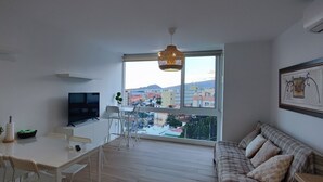 A modern living room with a large window, a dining area, and a sofa. - Descanso Asegurado en Ambiente de Calma (CN)