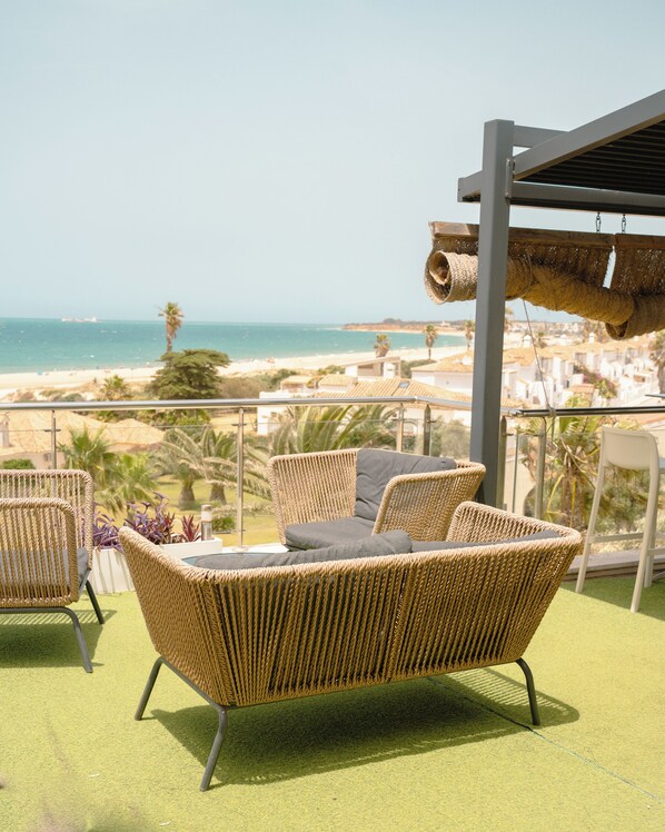 Un balcón con muebles de mimbre con vista a la playa.